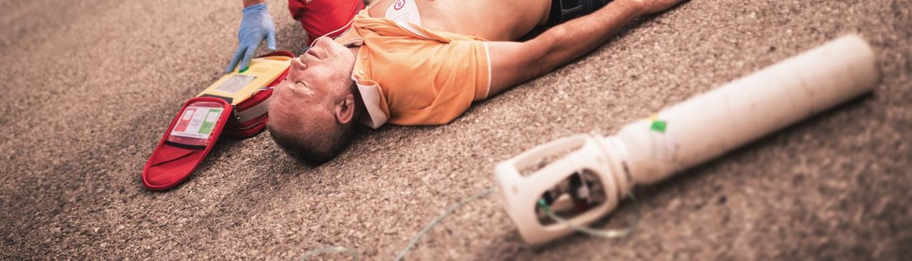Mann liegt am Boden daneben Sauerstoffflasche und Defibrillator